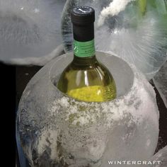 a bottle of wine sitting on top of a cement container filled with ice and snow