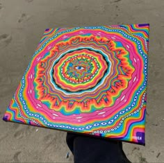 a person holding up a colorful umbrella on the beach