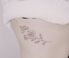 a woman's stomach with a rose tattoo on the lower part of her belly