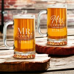 two personalized beer mugs sitting on top of a wooden table next to each other