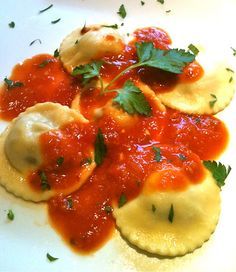 some ravioli with sauce and parsley on a white plate