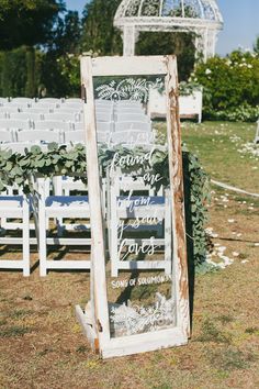 an outdoor ceremony with white chairs and greenery