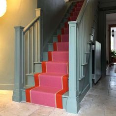 the stairs are painted pink and blue with red carpeting on them, along with an orange rug