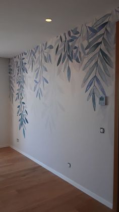 an empty room with white walls and blue leaves painted on it's wallpaper