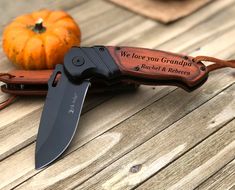 a knife is sitting on top of a wooden table next to a pumpkin and some leaves