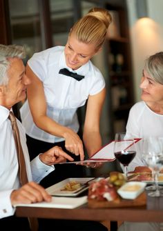 three people sitting at a table with food and wine