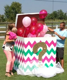 a man and two girls standing in front of a large box with balloons on it