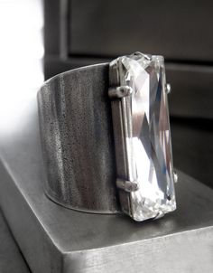 "Modern, minimalist, geometric. Stunning Swarovski crystal in sophisticated 'Black Diamond' with strong, architectural lines + form is featured on a modern + minimalist bezel. The wide, cuff-style antiqued silver-plated ring band fits very comfortably and is adjustable from approx. sizes 6.5 to 10+ (unisex sizing perfect for men + women). -Black Diamond Swarovski crystal: 8 x 24mm (5/16\" x 1\") -Adjustable wide cuff ring band: fits most sizes 6.5 to 10+ (unisex) -NOTE: Although this ring is adj Luxury Modernist Silver Men's Ring, Modern Crystal Open Ring With Vs Clarity, Modern Crystal Ring With Large Stone, Swarovski Crystal Rings, Band Fits, Cuff Ring, Sparkling Rings, Cuff Rings, Wide Cuff