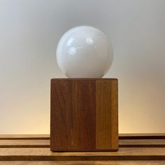 a white ball sitting on top of a wooden block