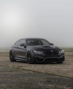 a gray car parked on top of a parking lot next to a foggy sky