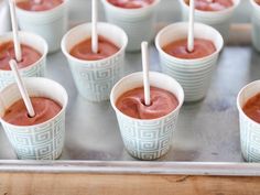 small cups with toothpicks in them are lined up on a metal tray and ready to be eaten