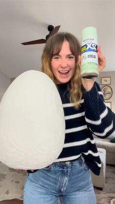 a woman holding up a large white ball and a can of toilet paper in her hands