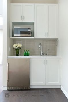 a kitchen with white cupboards and stainless steel dishwasher next to a silver refrigerator