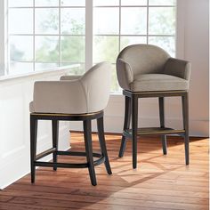 two upholstered stools in front of a window with white walls and wood flooring