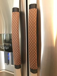 two handles on the door of a stainless steel refrigerator with brown and white patterned fabric