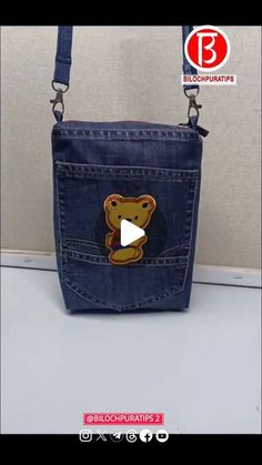 a small purse with a teddy bear on the front and side pocket, hanging from a hook