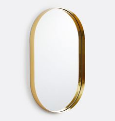 an oval mirror with gold trim around the edges on a white wall, against a plain background