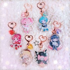 six keychains with cartoon characters on them sitting on a white surface in the shape of hearts