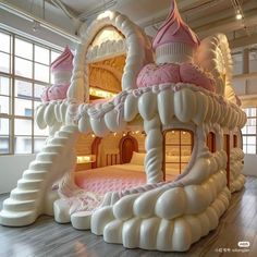 an inflatable castle bed with pink and white decorations on the walls, inside a large windowed room