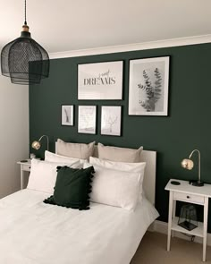 a bedroom with green walls and pictures on the wall above the bed, along with two nightstands