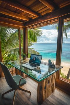 a laptop computer sitting on top of a glass desk in front of a large window