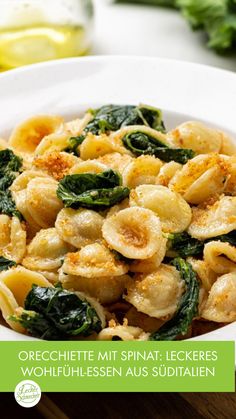 a white bowl filled with pasta and spinach