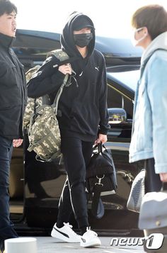 a woman in black hoodie and leggings carrying a bag while standing next to a man