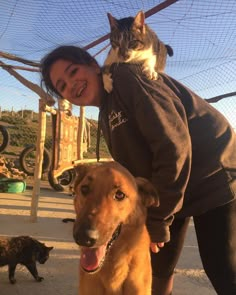 a woman standing next to a dog and cat