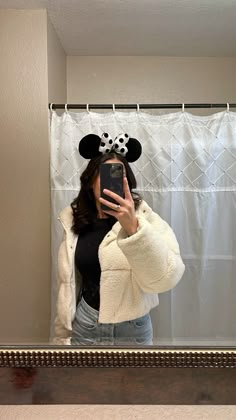 a woman taking a selfie in front of a mirror wearing a minnie mouse hat