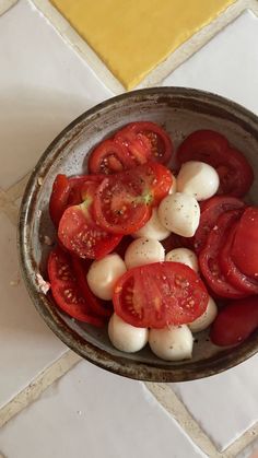 tomatoes and mozzarella in a bowl on a tiled floor next to a yellow wall