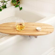 a glass of wine sitting on top of a bath tub next to a wooden tray