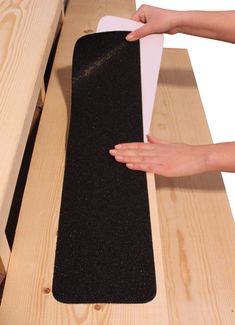 a person is holding a piece of black material near a wooden bench with a hand on it