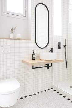 a white bathroom with black and white tiles on the floor, sink, mirror and shower stall