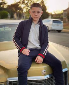 a young man sitting on the hood of a car