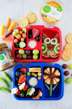 two plastic trays filled with fruit, crackers and an owl shaped lunch box