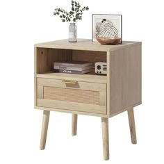 an end table with a drawer and some books on the bottom shelf, next to a potted plant