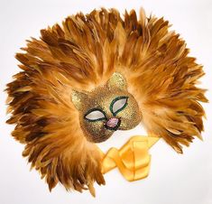 "The true king of the jungle! Crowned with layers of fluffy, golden rooster f feathers this mask is sure to impress!! Embellished with genuine swarovski crystals, ties with a 1.5\" satin ribbon and is lined with super soft, comfortable and easily wearable felt. NOTE: this mask takes at least a week to complete This mask will take center stage at any fete or gala, from Carnival in Brazil to New Year's in New York. Just be sure the event space has ceilings high enough to accommodate such a jaw-dro Extravagant Headpiece, Carnival In Brazil, Lion Mask, Lion's Mane, Rooster Feathers, King Of The Jungle, Lion Mane, Costume Masks, Colorful Feathers