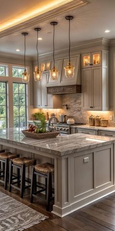 a large kitchen with lots of counter space and lights hanging from the ceiling over the island