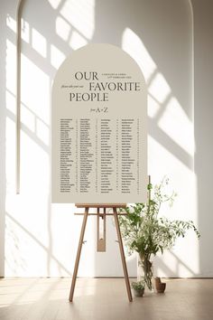 a white sign sitting on top of a wooden easel next to a potted plant