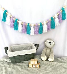 a teddy bear sitting on top of a bed next to a basket with tassels