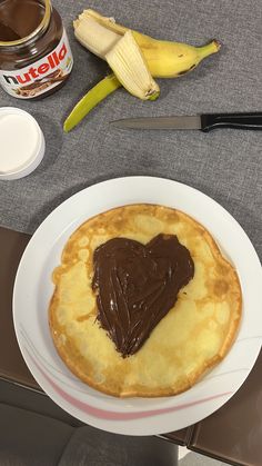 a heart shaped pastry on a plate next to some bananas