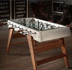 a foosball table sitting on top of a hard wood floor next to a chair