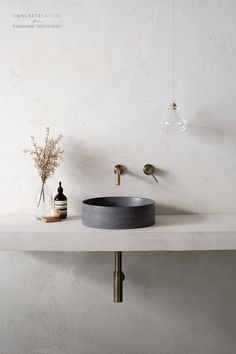 a bathroom sink sitting on top of a counter next to a vase with flowers in it