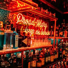 bottles and glasses are lined up on the shelves in a liquor store with neon lights