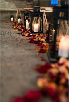 candles are lined up on the ground with rose petals