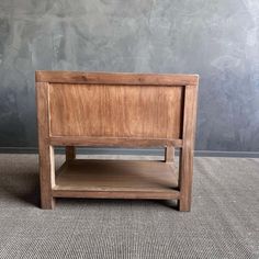 a wooden bed frame on carpeted floor with grey wall in the backround