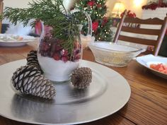 pine cones and berries in a glass vase on a silver platter with christmas decorations