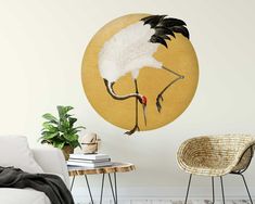 a white and black bird is standing in front of a yellow circle wall decal