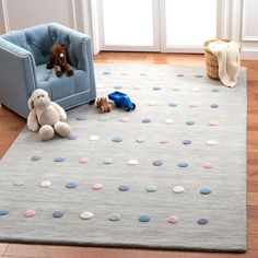 a child's room with a blue chair, teddy bear and toy cars on the floor