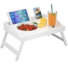 a tray with food and drinks on it, including an ipad sitting next to a bowl of fruit